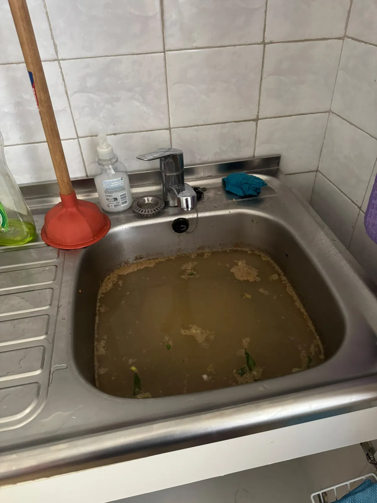 Évier de cuisine bouché, rempli d'eau grasse stagnante, avant le débouchage