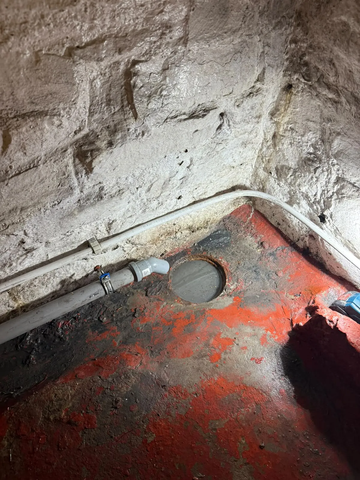Sterput au sol d'une cave, sol encore mouillé après le débouchage